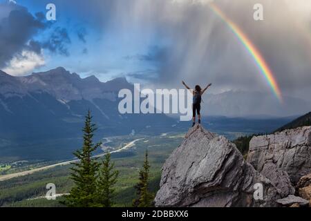 Adventurous Caucasian Girl with open arms is on top of rocky mountain Stock Photo