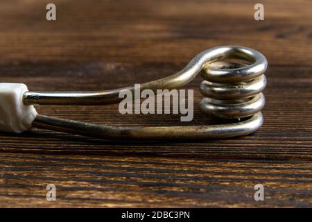 Old immersion water heater on dark wooden background. Close-up. Stock Photo