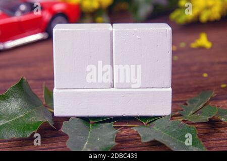 White wood calendar blocks for write the date and branches with yellow flowers over a wooden table. Selective focus with blurred background. Stock Photo
