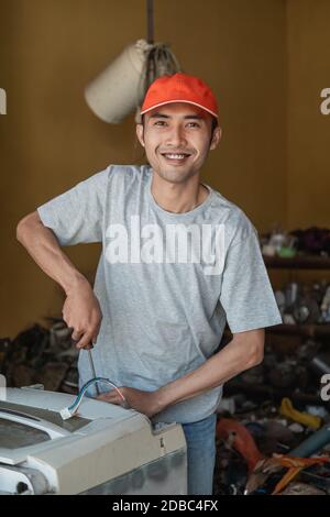 electronics workers smile at the camera using a screwdriver while repairing a washing machine at work Stock Photo