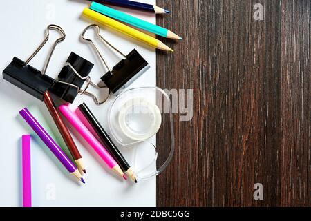 Set of colored pencils, paper clips on the wooden table with white paper. Stationery supply and office equipment backgrounds Stock Photo