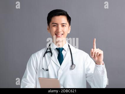 smiling young male doctor hand pointing up Stock Photo