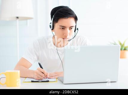 smiling young man working from home with laptop Stock Photo