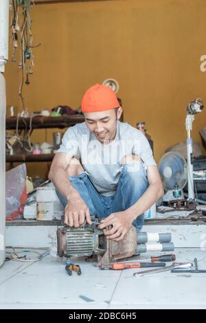 asian man electronics worker holding water pump machine for repair in electronics service shop Stock Photo