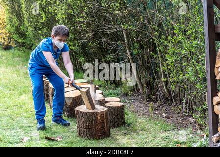 Boy chops wood wearing protective face mask Stock Photo
