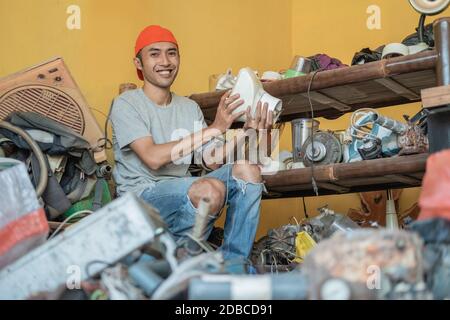electronics repairman smiles at the camera while handling a faulty blender at a service shop Stock Photo