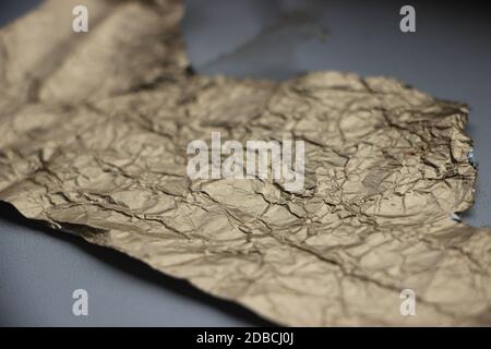 Crumpled and torn golden bronze shiny foil texture background Stock Photo