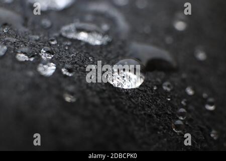 Water drops on black leather background texture. Macro Closeup. Stock Photo