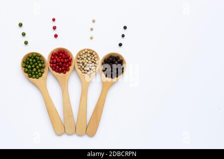 Green, red, white and black peppercorns with wooden spoon on white Stock Photo