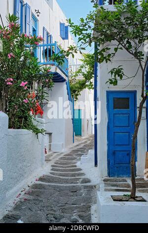 Picturesque scenic narrow streets with traditional whitewashed houses with blue doors windows of Mykonos Chora town in famous tourist attraction Mykon Stock Photo