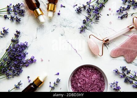 Set of natural organic SPA cosmetic with lavender. Flat lay bath salt,  essential oils, face roller,  on marble background. Skin care, beauty treatmen Stock Photo