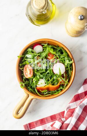 Fresh arugula salad with radishes, tomatoes and red peppers in bowl. Stock Photo