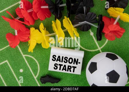 Saison Start in german language means season beginning. Soccer Ball with flower necklace in the colors of german flag and calendar Stock Photo