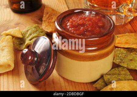 Vegetable tortilla chips and salsa with a mug of beer in the background Stock Photo