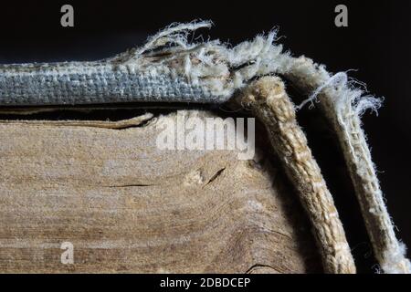 Macro of vintage book pages and worn spine on dark background. Wisdom, education or book repair concept. Stock Photo