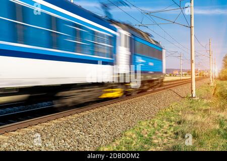 train going to a stop opposite the sun. Stock Photo