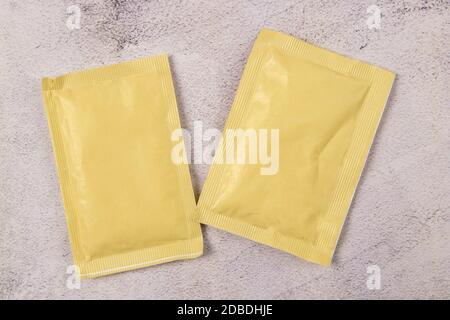 Two white paper sachets isolated on marble background. Top views with clear space. Stock Photo