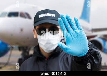 Security Guard Making Stop Gesture Near Airplane Stock Photo