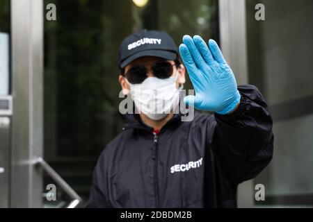 Security Guard In Uniform And Face Mask Making Stop Hand Gesture Stock Photo
