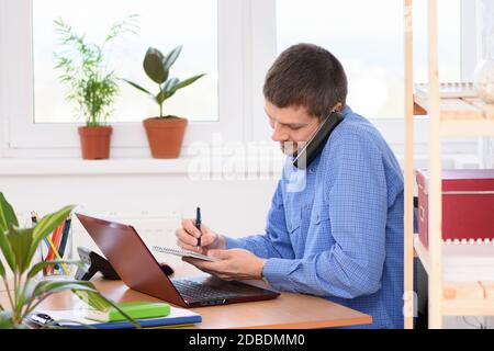 Businessman talking on the phone and taking notes in a notebook Stock Photo
