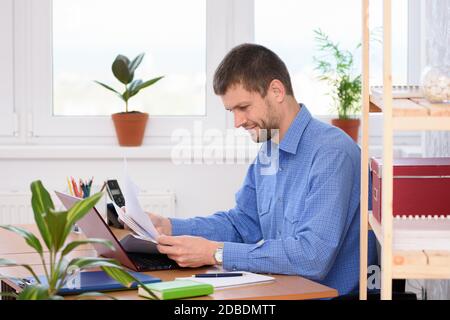 Successful young man reads documents while sitting at a table in the office Stock Photo