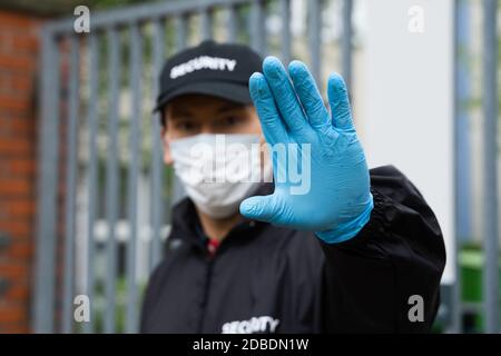 Security Guard In Uniform And Face Mask Making Stop Hand Gesture Stock Photo