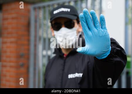 Security Guard In Uniform And Face Mask Making Stop Hand Gesture Stock Photo