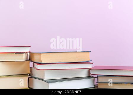 Stacks of books several on a pink background close-up. Hardcover books in different colors. At the top there is a free space for the inscription, text Stock Photo
