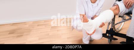 Doctor Looking At Patient Leg Cast With Broken Bone Injury Stock Photo