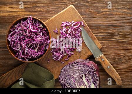 Cut red cabbage on chopping board on wooden background, top view. Vegetarian, slimming, diet food concept. Stock Photo