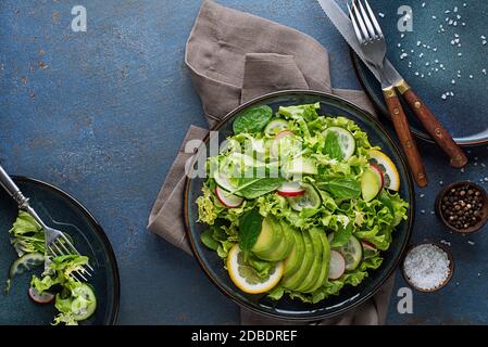 Green salad with avocado and fresh vegetables on a blue background Stock Photo