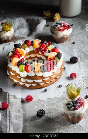 round pie with berries and cupcake on a gray background Stock Photo
