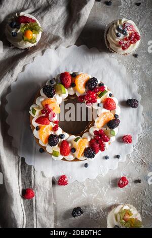 round pie with berries and cupcake on a gray background Stock Photo