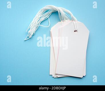 stack of empty white rectangular paper tags on a rope, blue background, item for luggage, price tag Stock Photo