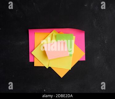 empty paper multi-colored stickers are glued on a black board, place for an inscription Stock Photo