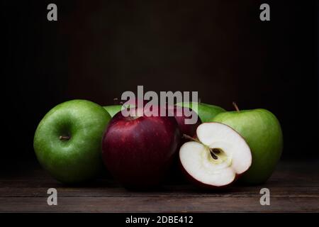 Group of red and green apples on rustic wooden surface with dark background and copy space Stock Photo