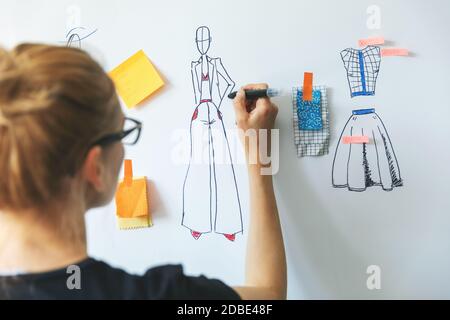 fashion designer sketching new clothing collection on whiteboard