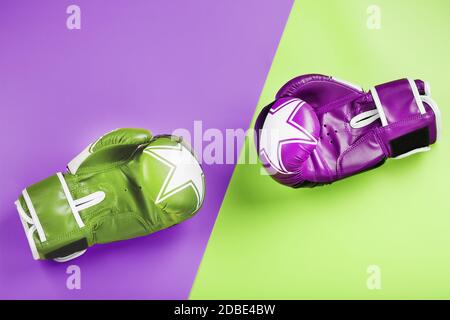 A pair of green and pink boxing gloves on a light green and pink background. The concept of overcoming difficulties. Feminism, the struggle for the di Stock Photo