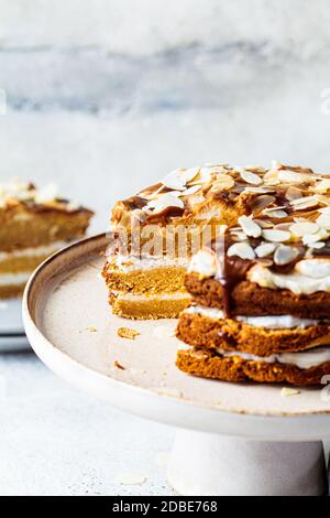 Vegan cake on a cake plate. Homemade carrot cake with white cream, caramel and nuts. Stock Photo
