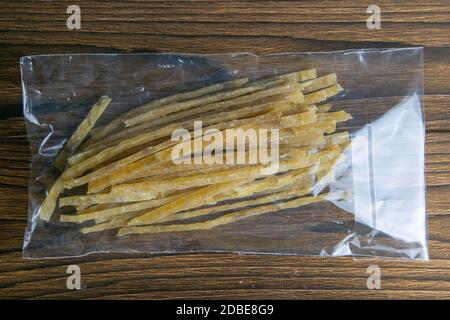 Dried salted tuna elite snack in a transparent package appetizer to beer on wooden background. Snack Fish to beer. Close up. Stock Photo