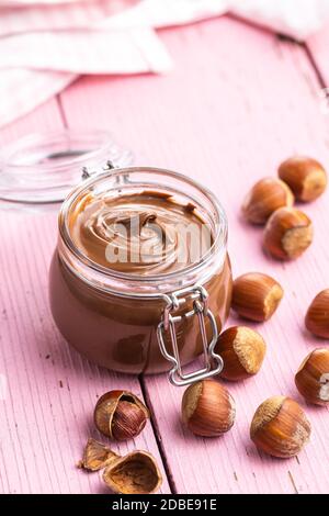 Sweet hazelnut spread. Chocolate cream in jar on pink table. Stock Photo