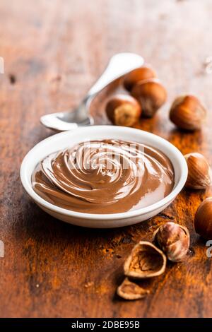 Sweet hazelnut spread. Chocolate cream in bowl on wooden table. Stock Photo