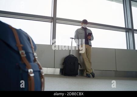 young asian man male air traveler reading e-book using a e-reader while waiting for boarding in airport terminal building Stock Photo