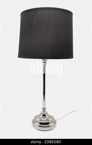 A modern floor lamp with a black lampshade and chrome-colored base Stock Photo