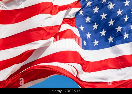 American flag waving in the wind on blue sky, US flag motion close-up, red white blue flag outdoors in sunlight. United States of America national flag. USA stars and stripes Stock Photo
