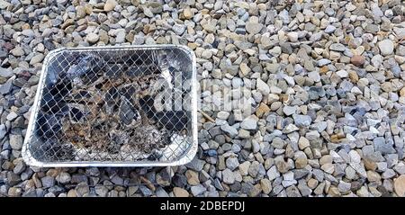 Burning coal heated disposable grill on stone background ground. black coal. ready for barbecue Stock Photo