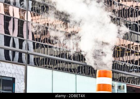 Close up picture of a steam pipe on the street of Manhattan with modern building in background, New York, USA. Stock Photo