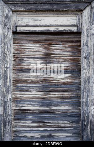 Closed, heavily weathered wooden roller blind in portrait format Stock Photo