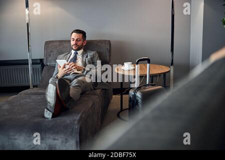 Resting entrepreneur scrolling through his white tablet Stock Photo