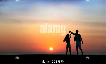 Happy Romantic young Couple dancing on the beach at sunset Stock Photo